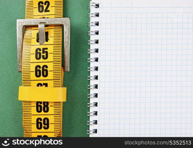 meter belt slimming and notepad on the green background