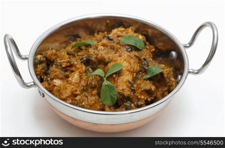 Methi murgh - chicken cooked with fresh fenugreek leaves - in a kadai, or karahi, traditional Indian wok, over white.