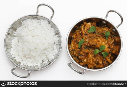 Methi murgh - chicken cooked with fresh fenugreek leaves - in a kadai, or karahi, traditional Indian wok, over white, garnished with fenugreek leaves and seen from above next to a bowl of basmati rice