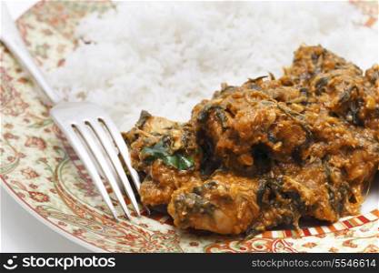 Methi murgh - chicken cooked with fresh fenugreek leaves on a plate with basmati rice and a fork