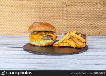 Mexican beef burger with melted cheddar cheese, sliced jalapenos, guacamole, sesame seed bread and paprika fries
