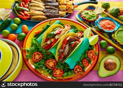 Mexican chicken and beef fajitas tacos in colorful table with sauce