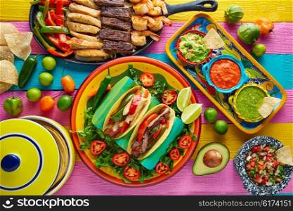 Mexican chicken and beef fajitas tacos in colorful table with sauce