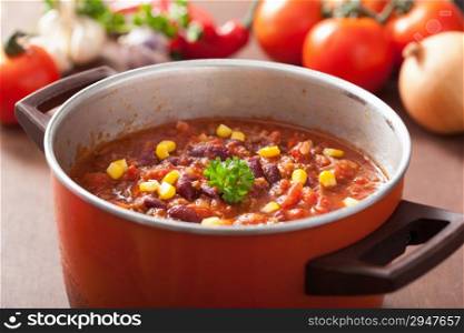 mexican chili con carne in red rustic pot with ingredients