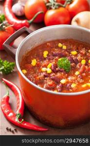 mexican chili con carne in red rustic pot with ingredients