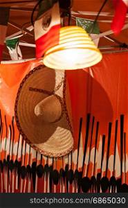 Mexican flags and sombrero hanged in a stand for a party. Mexican sombrero hanged in a stand