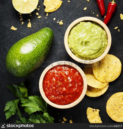 Mexican food concept: tortilla chips, guacamole, salsa and fresh ingredients over vintage rusty metal background. Top view
