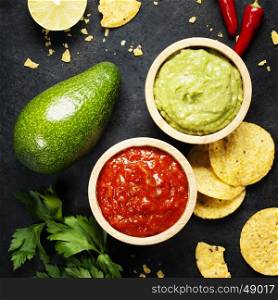 Mexican food concept: tortilla chips, guacamole, salsa and fresh ingredients over vintage rusty metal background. Top view