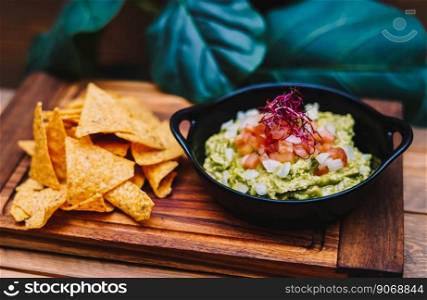 Mexican guacamole with nachos chips on wooden board