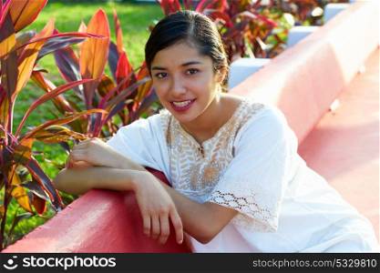 Mexican latin woman with ethnic dress sitting in garden park bench