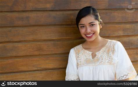 Mexican latin woman with ethnic dress smiling in wooden background