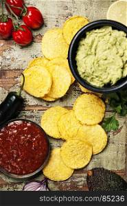 Mexican nachos chips with homemade fresh guacamole sauce and salsa over old background. Top view. Mexican food concept