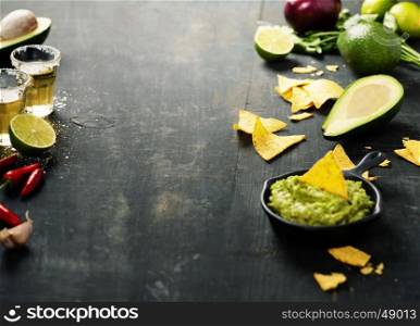 Mexican nachos chips with homemade fresh guacomole sauce over old background. With space for text