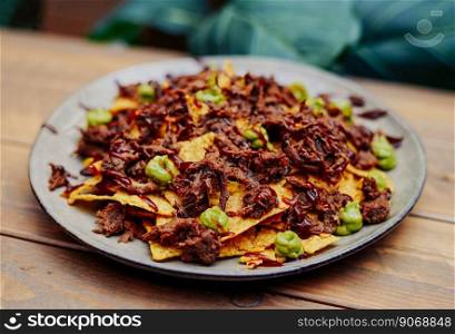 Mexican nachos with beef and chilli on wooden table