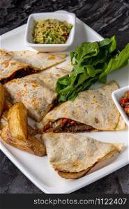 Mexican quesadilla with meat, salad and peppers on marble table. tasty Mexican quesadilla