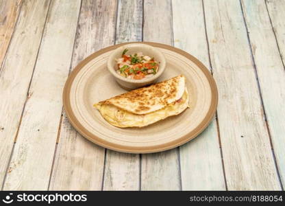 Mexican quesadilla with wheat tortilla stuffed with melted cheese and ham with pico de gallo and cilantro
