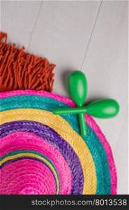 Mexican sombrero, blanket and pair of maracas on wood background.
