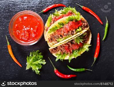 mexican tacos with meat and salsa on a dark background, top view