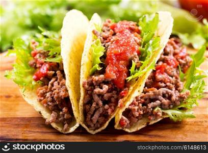 mexican tacos with meat and salsa on a wooden table