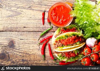 mexican tacos with meat and salsa on a wooden table, top view