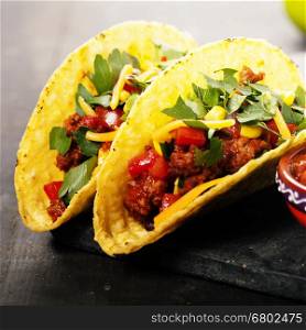 Mexican tacos with meat, beans and salsa on rustic background