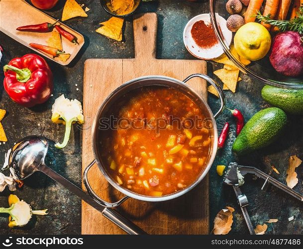 Mexican vegetarian bean soup in cooking pot with ladle on rustic kitchen table ingredients and cutting board, top view. Vegan or vegetarian healthy food concept