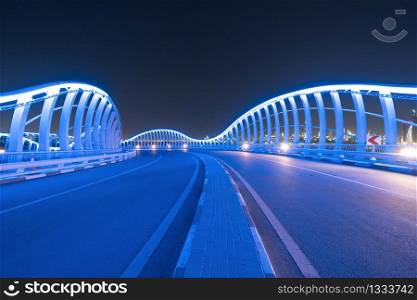Meydan Bridge and street road or path way on highway with modern architecture buildings in Dubai Downtown at night, urban city at night, United Arab Emirates or UAE.