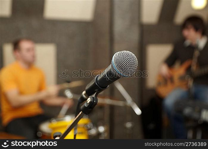 microphone. drummer and guitar player in out of focus