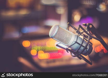 Microphone in a professional recording or radio studio, equipment in the blurry background