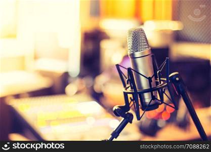 Microphone in a professional recording or radio studio, equipment in the blurry background