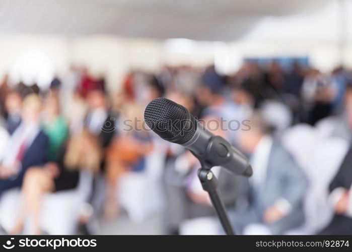 Microphone in focus against blurred audience. Participants at the business or professional conference.