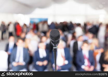 Microphone in focus against blurred audience. Participants at the business or professional conference.