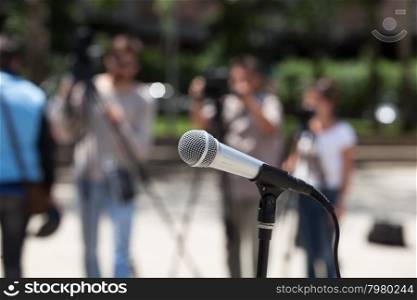 Microphone in focus against blurred journalists