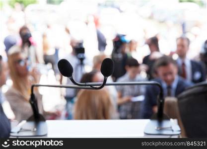 Microphone in focus at press or public event, blurred people in the background