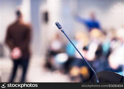 Microphone in focus, blurred speaker and audience at business conference, presentation or international political event in the background