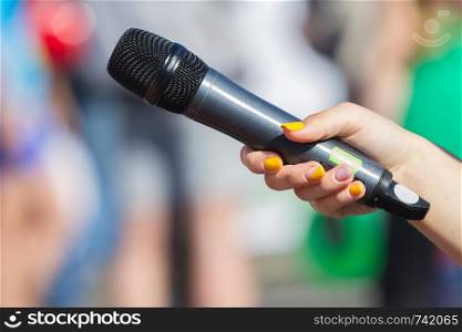 Microphone in hand close up in a street interview