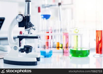 Microscope and test tubes with lab glassware in laboratory background, research and Scientific concept