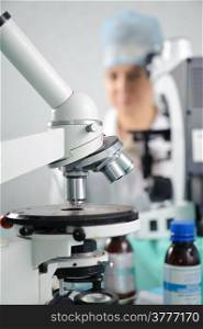 Microscope in the laboratory. Closeup. Blurred silhouette of a doctor in the background.