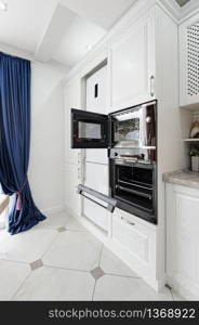 microwave and oven doors open in interior of modern white wooden kitchen. modern white wooden kitchen interior