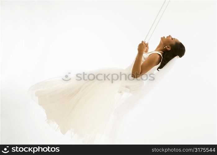 Mid-adult African-American bride swinging with white background.