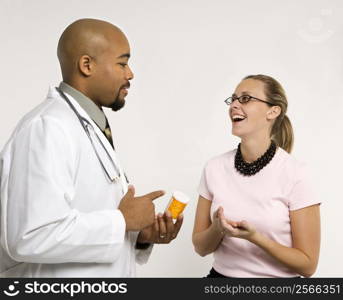 Mid-adult African-American doctor and Caucasion mid-adult female patient discussing medication.