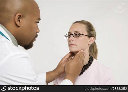Mid-adult African-American doctor examining Caucasion mid-adult female patient.