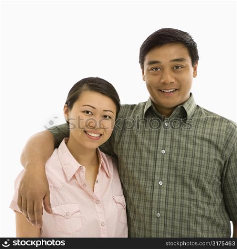 Mid adult Asian couple with arms around eachother smiling.
