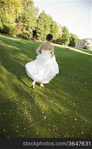Mid-adult bride running in park