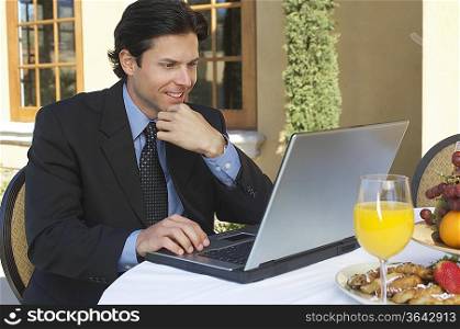 Mid adult business man working on laptop at outdoor cafe table