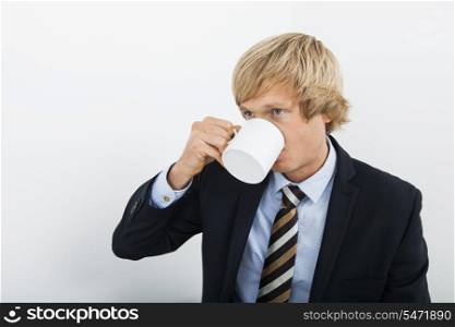 Mid adult businessman drinking coffee over white background