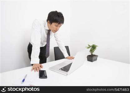 Mid adult businessman looking at laptop in office
