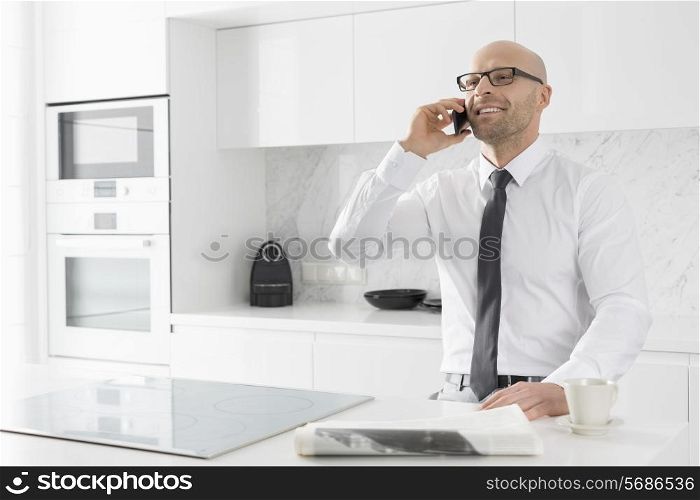 Mid adult businessman on call at kitchen counter