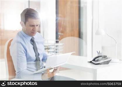 Mid adult businessman reading documents in office