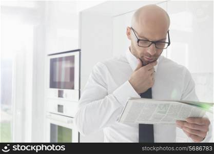 Mid adult businessman reading newspaper at home
